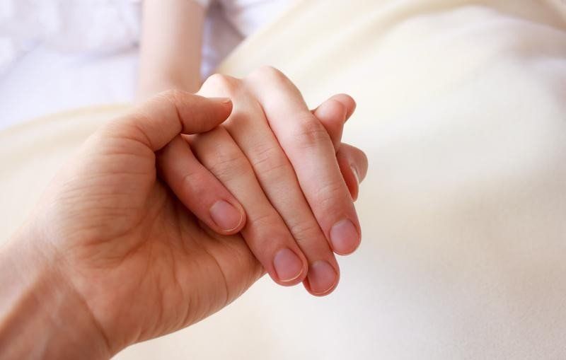 A close up of a person holding another person 's hand.